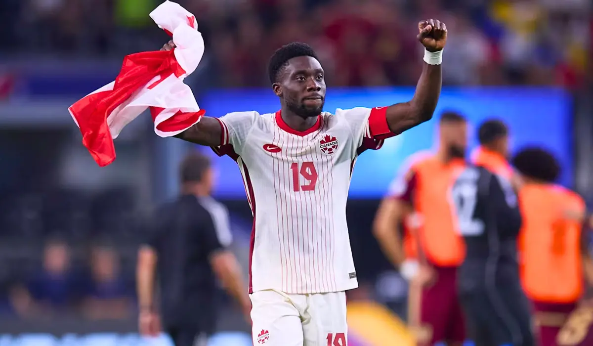 Alphonso Davies giơ tay ăn mwufng. 